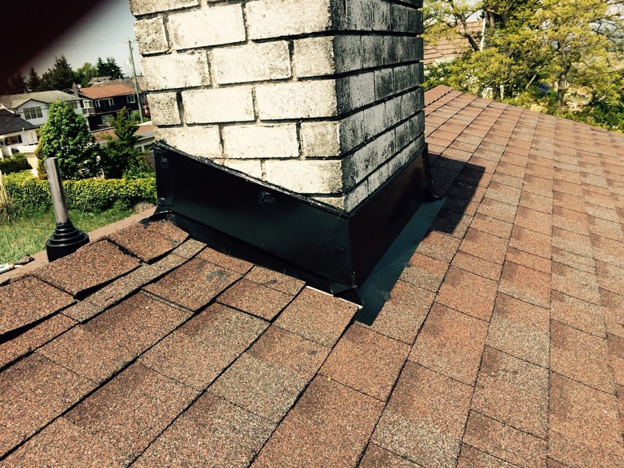 New flashing fitted around a brick chimney on a shingle roof